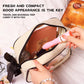 Hand placing the pink Breeze Lipstick Vibrator into a beige cosmetics travel bag next to makeup palettes.