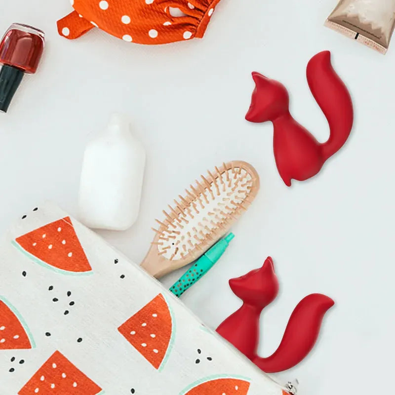 Discreet lifestyle flatlay of Foxy red fox G-spot vibrator beside a travel cosmetic bag